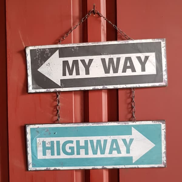 Photo of two signs that point to different directions. One says my way and the other one says highway.